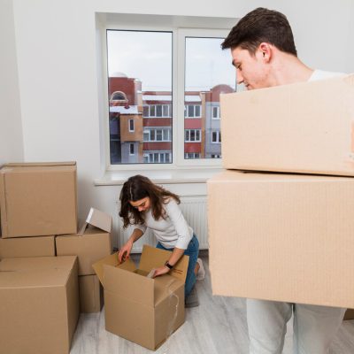 man-carrying-cardboard-boxes-looking-her-girlfriend-unpacking-box-new-home_23-2148060130